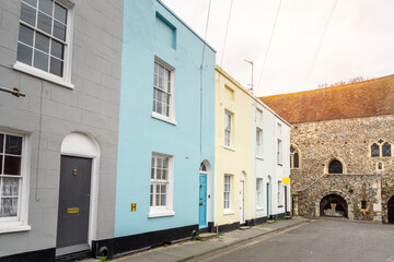 Row of colourful terraced houses in an old city centre on a cloudy spring day. A real estate sign reading sold is by the door of the last house in the  row.