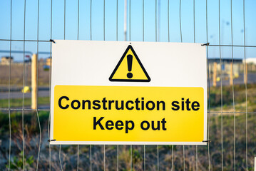 Keep out sign on a metal fence at a construction site at sunset