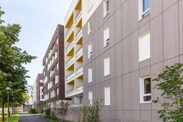 Modern apartment buildings along a tree lined pavement on a clear summer day