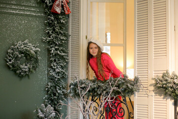 A banner featuring a sweet girl in a pink suit and a milky beret standing on a balcony in a festively decorated room with windows overlooking a cafe terrace. A wonderful mood. A trip for the Christmas