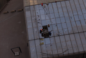 workers are repairing the roof of glass windows