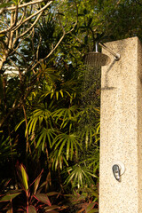 Naklejka premium Outdoor shower flowing in tropical garden, water drops on stone. Concept: calm wellness nature
