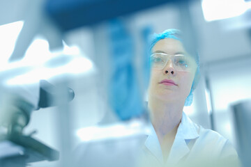 Focused Caucasian female scientist with red hair using micropipette in sterile lab. Young...