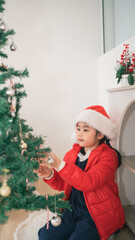 A Young Girl in a Christmas Hat Decorates a Festive Tree with Ornaments and Joyful Anticipation for the Holiday Season and Family Celebrations