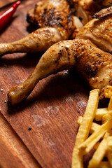 Macro close-up of a juicy grilled chicken leg with crispy French fries, ready to eat.