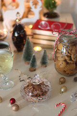 Cookie jar, tea, wine, nuts, books, lit candles and Christmas decorations on the table. Cozy Christmas hygge at home. Selective focus.