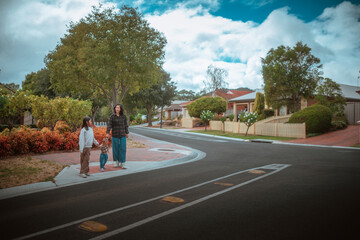 A mother and her child are standing together on a suburban street, enjoying life