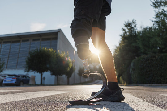 Confident stride walk of a man wearing an artificial leg, an orthopedic prosthesis, going across the street on a zebra crossing.
