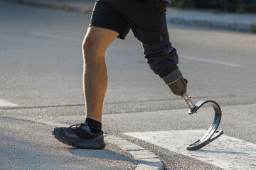 Man using a prosthetic leg with a versatile foot designed for walking and running, enjoying a sunny day while crossing the street.