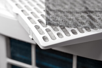 Disassembled air purifier with used mesh filter on dusty plastic white cartridge closeup