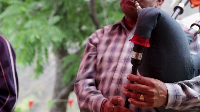 A village man plays a traditional wind instrument during a poor rural wedding ceremony in Uttarakhand, India, showing poverty, folk culture, community bonding, and mountain village life.