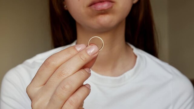 
A broken heart after betrayal. A woman holds a wedding ring, a painful process of letting go.