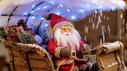 Santa claus figurine riding wooden sleigh under blue lights with falling snow decoration for christmas - Powered by Adobe