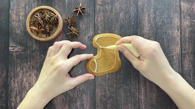 A man decorates a delicious Christmas gingerbread sock with sweet icing. 