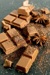 On a black background there are pieces of cocoa chocolate with sugar on a spoon.	