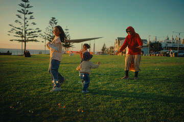 A joyful family enjoys playful activities in a park at sunset, surrounded by nature
