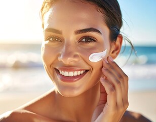 Close-up of a smiling woman applying sunscreen on her cheek near a sunlit beach. She?s looking at the camera