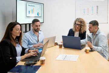 Business colleagues collaborating on laptops during an office meeting