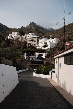 Scenic view of the quiet mountain village of Taganana, Tenerife, with white houses nestled on a hillside under a cloudy sky, creating a peaceful atmosphere.
