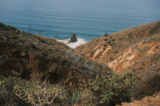 Scenic coastal landscape of Almaciga, Tenerife, with rocky cliffs and dry vegetation overlooking the calm blue sea under a clear sky.