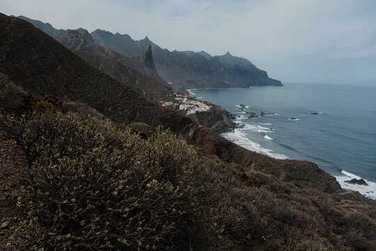 A dramatic coastal landscape of Almaciga, Tenerife with rugged cliffs and rocky shoreline under a moody sky, showcasing natural beauty and ocean views and part of Benijo beach.