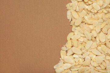 Fresh almond flakes on brown background