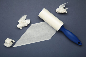 Cloth fabrics cleaner lint roller brush with paper roll on dark blue background. Sticky roller, pet cat dog fur dust hair remover