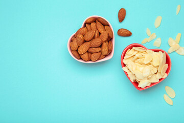 Fresh almond flakes and nuts in bowl on blue background