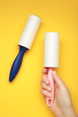 Woman holding lint roller on yellow background. Top view