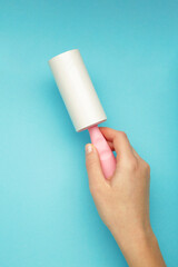 Woman holding lint roller on blue background. Vertical photo