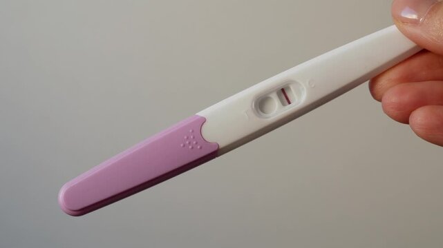 A negative pregnancy test in a woman's hand. Close-up of an emotional reaction.