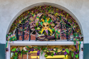 Mardi gras decor with carnival mask and beads at a window in a street of New Orleans, Louisiana