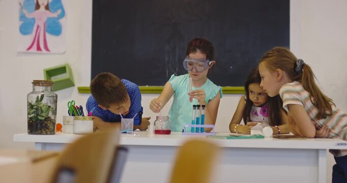 Curious elementary school children doing science experiment in classroom, girl using test tubes and goggles, STEM education, teamwork and learning in modern primary school lab.