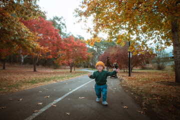 A joyful child runs along a beautiful path surrounded by colorful autumn leaves