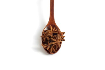 A wooden spoon with anise stars lies on a white background.	