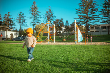 child explores park during sunset, child exploring grassy park with trees during golden