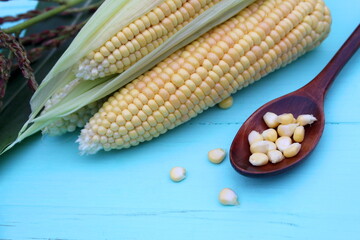 There is a spoon with fresh corn on the table.