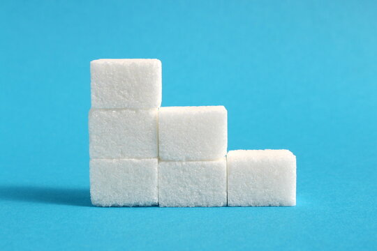 Refined sugar is stacked in ascending order on a blue background.	