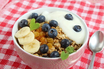 There is a bowl of dry breakfast cereal on the wooden table.	