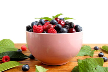A large plate with fresh berries stands on a wooden table.	
