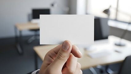 Hand presenting a blank white business card with copy space against a modern office background, ideal for corporate branding and contact information