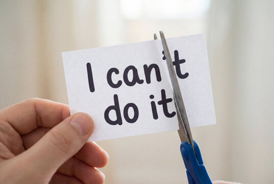 Person cutting paper with 'I can't do it' to overcome negative thoughts