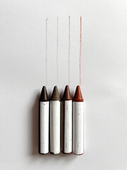 Four furniture repair crayons lie on paper above color test lines in various wood tones