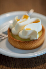 Light and refreshing lemon tart topped with whipped cream on a rustic wooden table setting