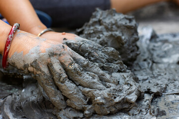 Young woman sculpting clay idol by hand during traditional craft process