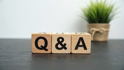Three wooden blocks spell Q and A on dark surface. A potted plant sits in soft focus background. Concept of questions and answers communication.