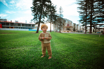 A joyful child standing barefoot on lush green grass in a beautiful park