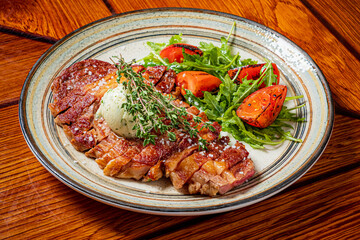 Grilled steak sits on a plate with fresh herbs and roasted tomatoes, ready to be enjoyed