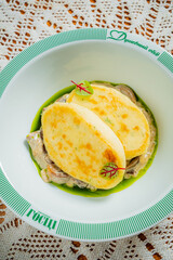Golden potato dumplings on rich mushroom sauce, with fresh greens on a delicate plate