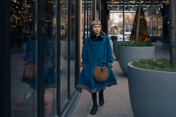 Teen girl walking in festive snowless city decorated for Christmas